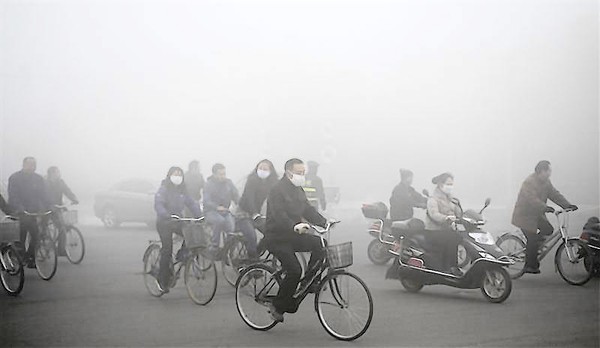 People ride along a street on a smoggy day in Daqing
